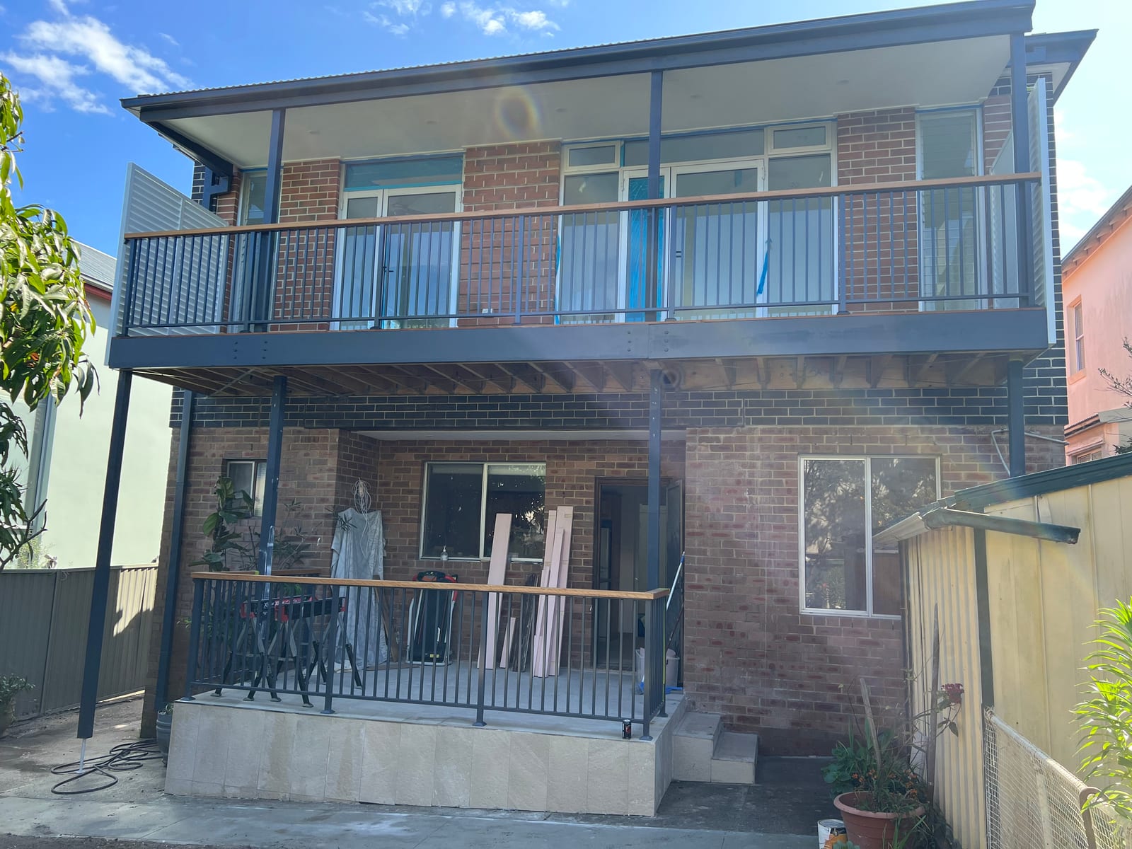 After — The original single-storey rear yard before the renovation, and the same rear elevation after the home was taken up to two storeys with a new balcony