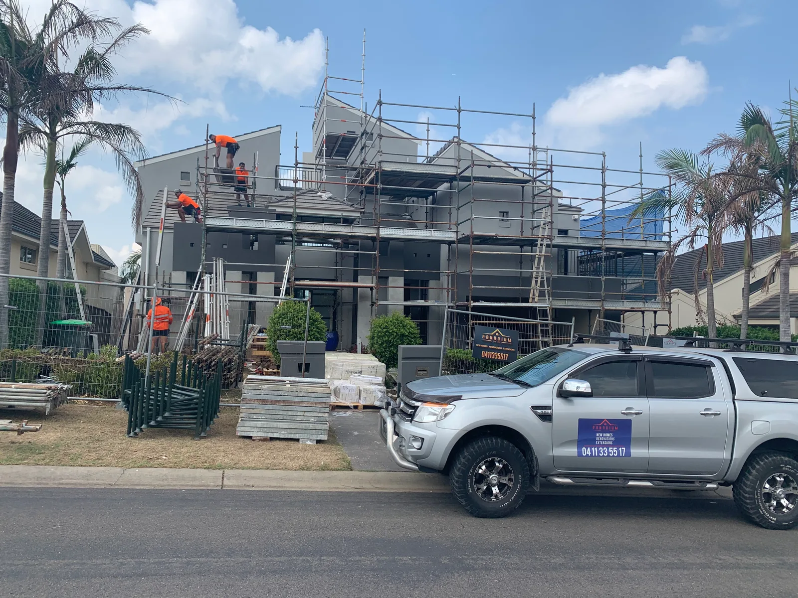Before — The Castle Hill home fully scaffolded during construction with a Panadium site sign and liveried ute out front, and the same street elevation after the completed two-storey render facade