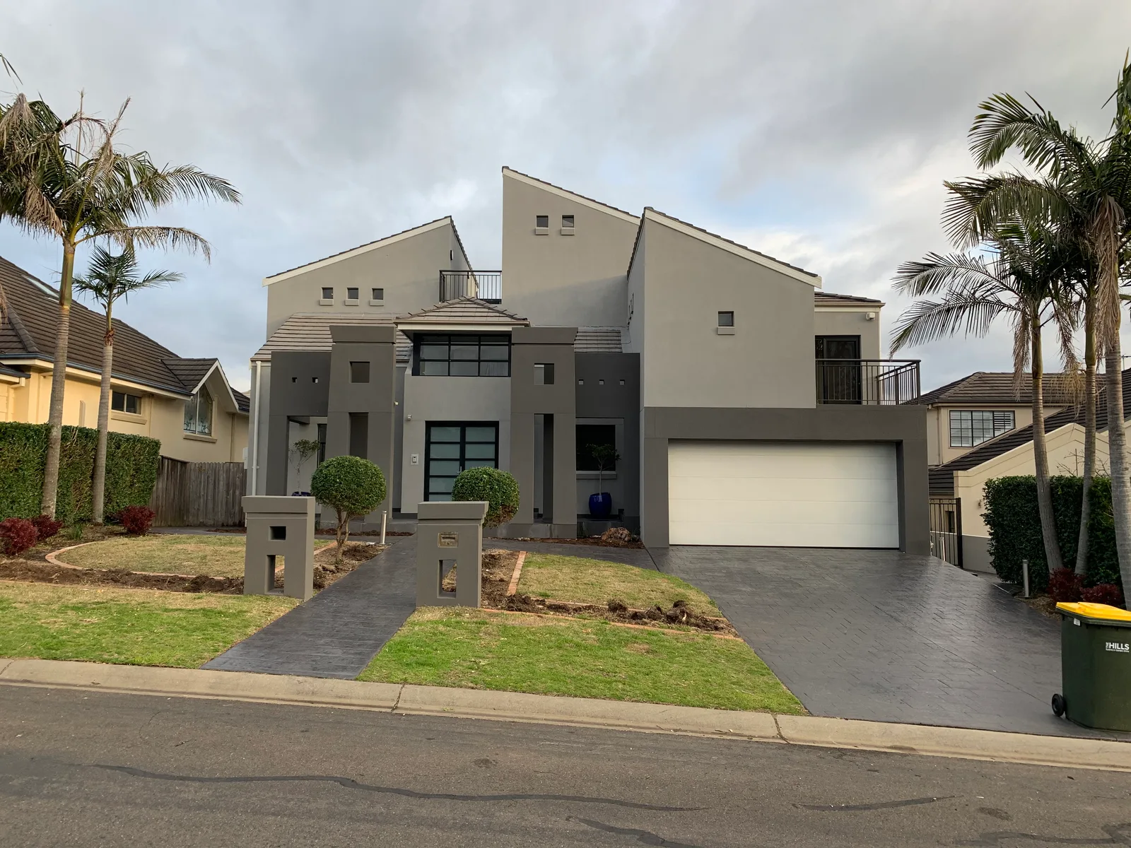 The completed two-storey Castle Hill home viewed from the street in daylight — a rendered facade with a double garage and landscaped front garden.