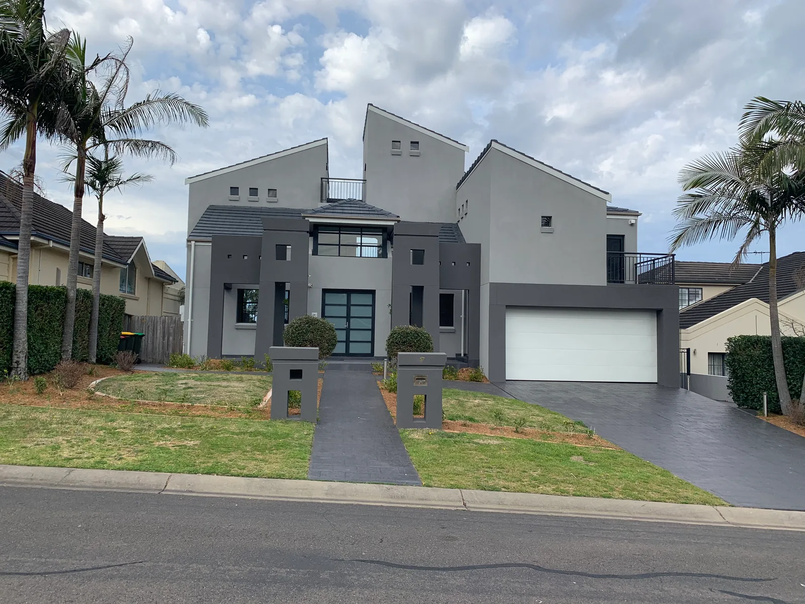After — The Castle Hill home fully scaffolded during construction with a Panadium site sign and liveried ute out front, and the same street elevation after the completed two-storey render facade