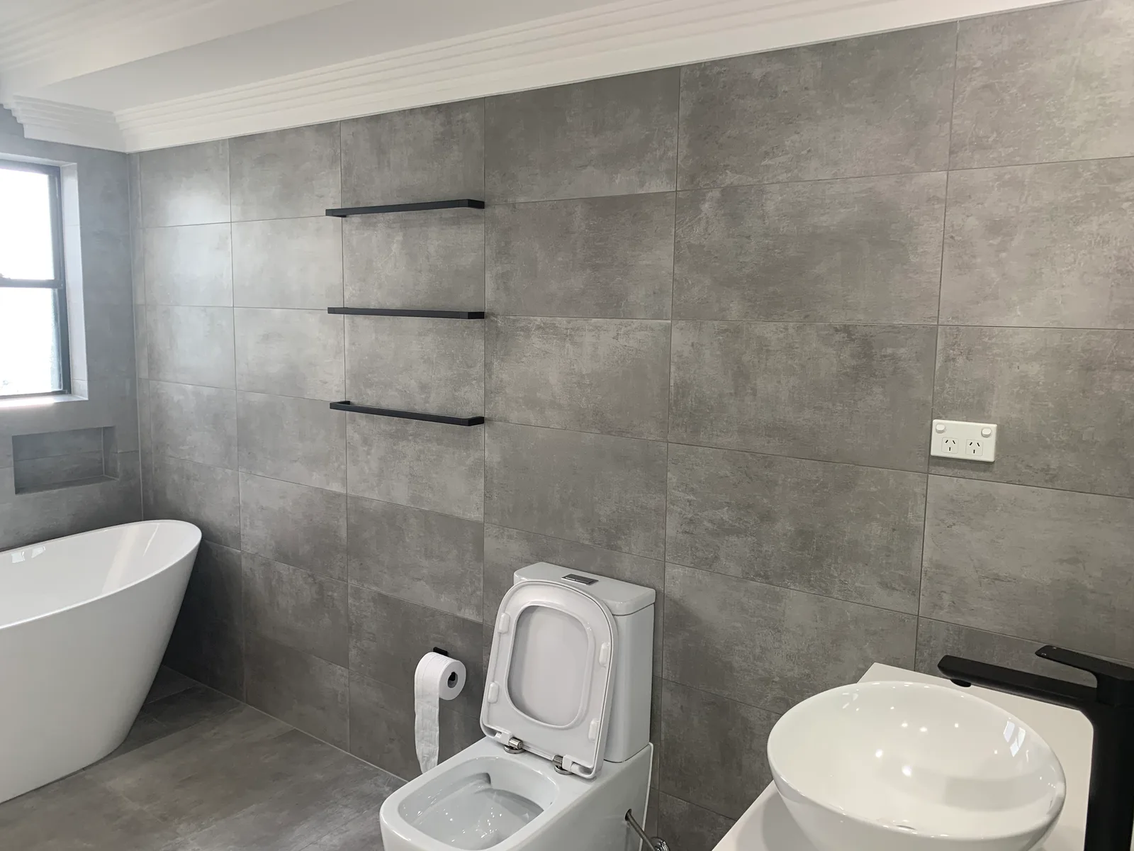 A finished bathroom with a wall-mounted toilet and a pedestal-style basin.