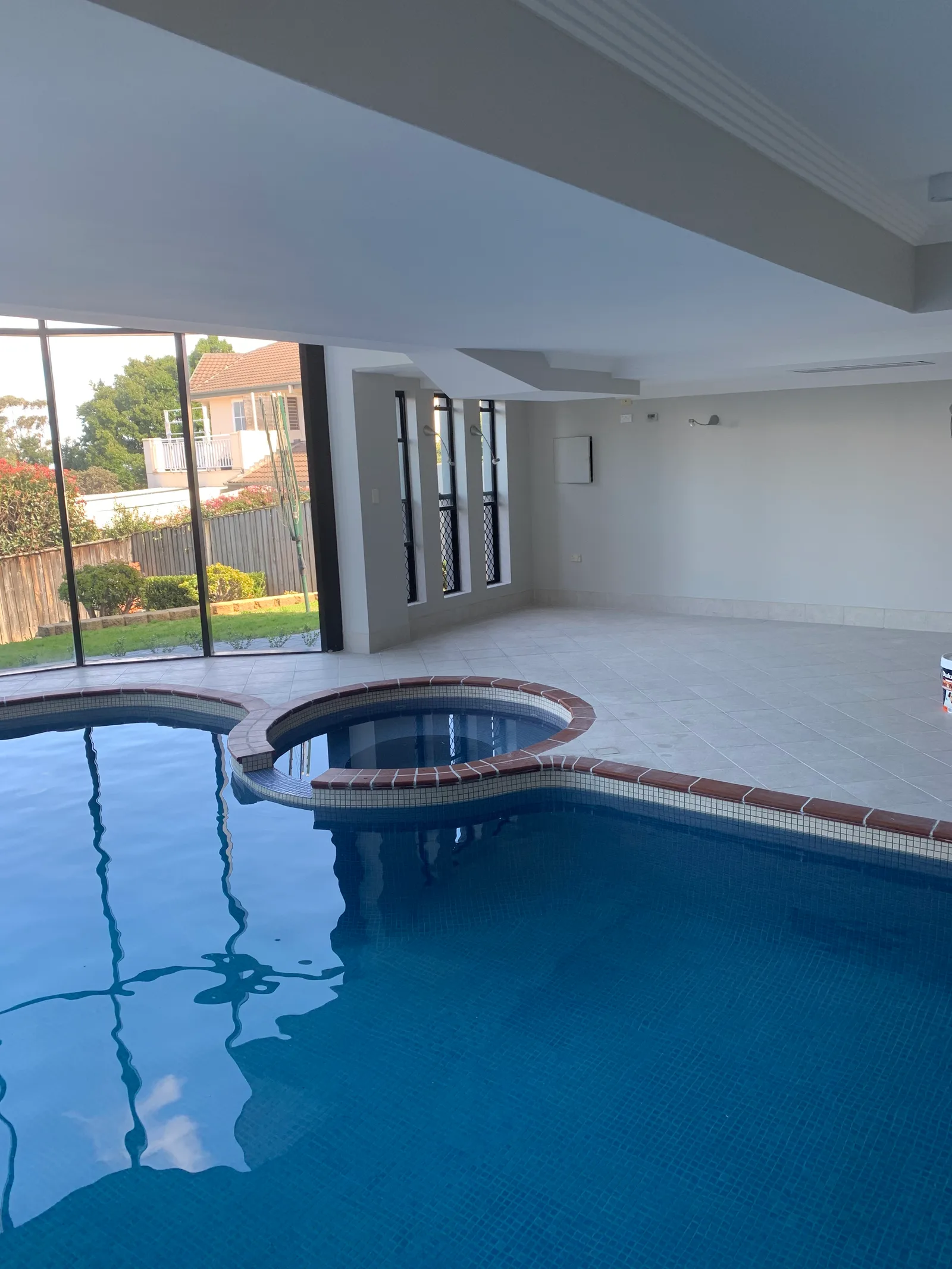 Before — The new indoor pool and spa room during construction with the structure and glazing framework in place, and the same room finished and styled at dusk