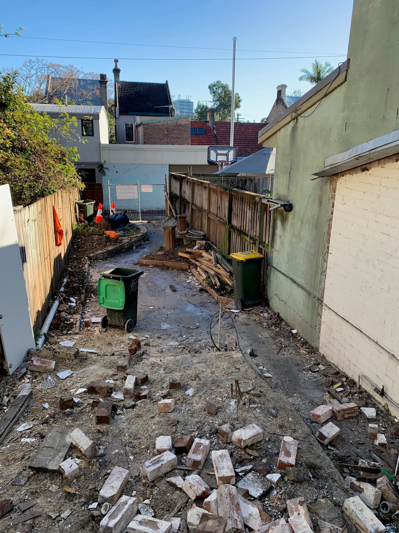 The rear of the site cleared during construction, with temporary fencing, waste bins and demolition material along a narrow laneway.
