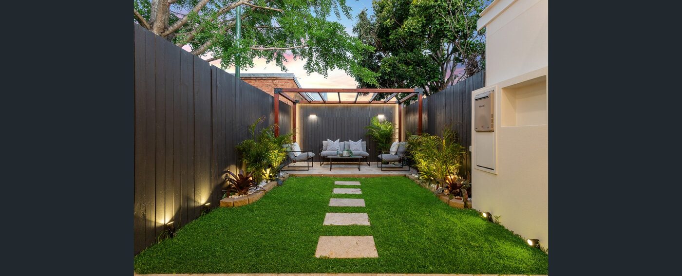 The landscaped rear courtyard — paving, lawn and a covered entertaining area