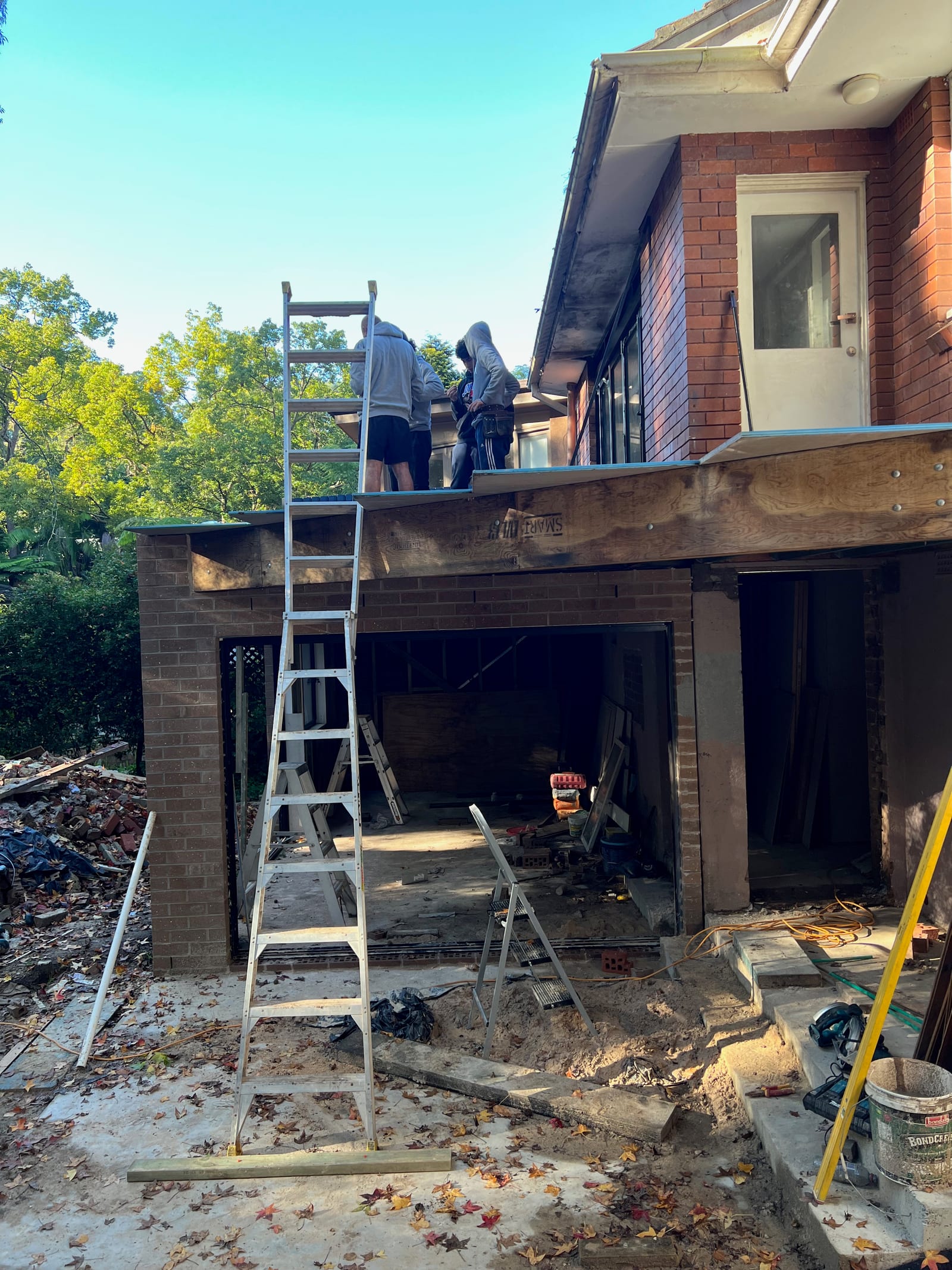 Timber roof framing going on over the new lower-ground level's brick shell, which becomes the paved patio above