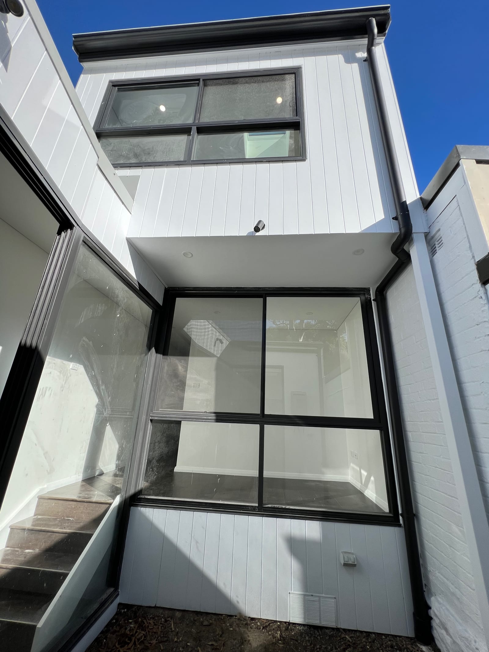 During construction — the rear elevation from below, showing a genuine new first floor built above the extension, both levels with black-framed windows